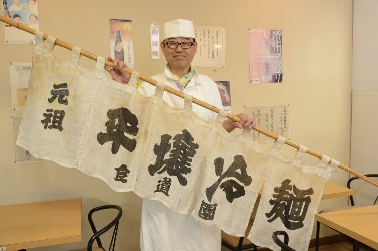 カルビクッパ800円ほか。お店の暖簾を持つ上田さん。