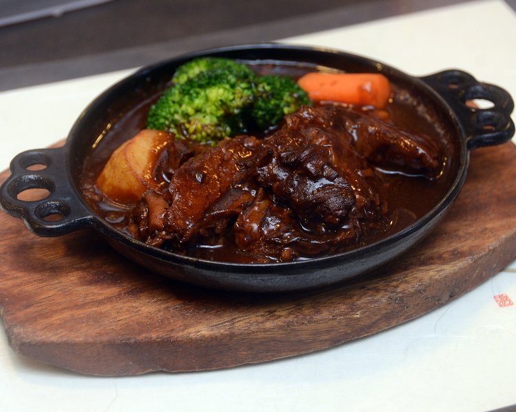 これがお店1番人気のビーフシチュー2500円。お皿ではなく焼いた鉄板の上に盛り付けられて提供されるのが最大の特徴。ライスorパンの追加オーダーがお約束に。