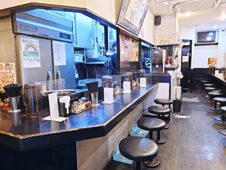 カウンター20席。通路を挟んで調理場向きと壁向きにそれぞれ席があり、どちらを向いても山岸マスターの書がある。