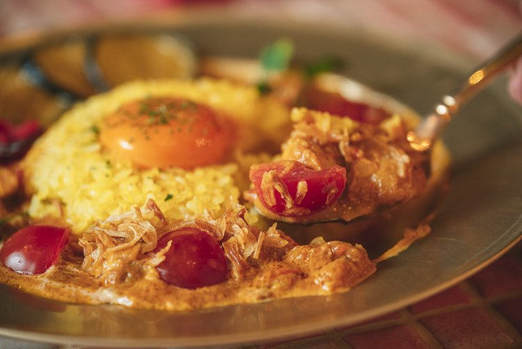 やわらかいチキンがまろやかなルーと絡み合い、トマトや福神漬けなどの具材が交互にアクセントとなる。