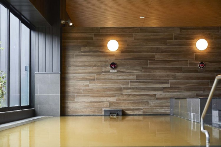 加水なしの源泉を注ぐ上段の浴槽は、湯船の底が見えないくらいの茶褐色だ。