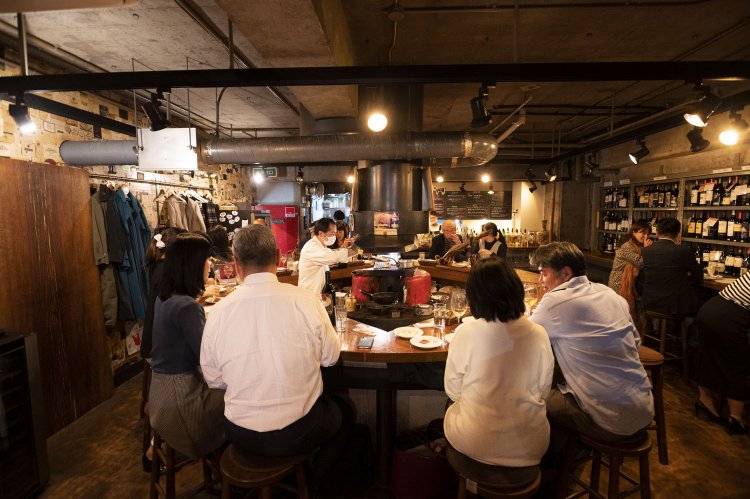 壁面や階段脇の冷蔵庫からスタッフとともにワインを選ぶのも楽しい。「円形カウンターの中央で焼く炭火焼きもぜひ！」。