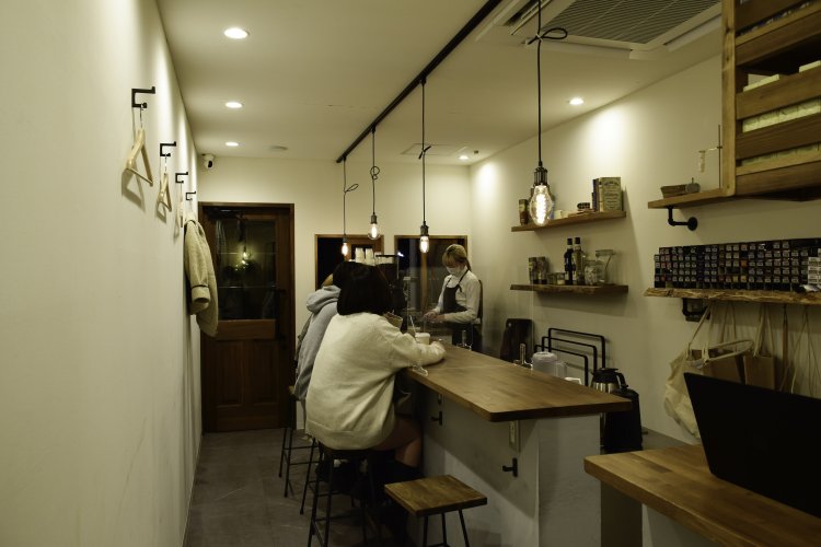 さりげなく置かれたインテリアにセンスが感じられるシンプルな店内。カウンター内とレジ上の棚に美容室で使うカラーやシャンプーが置かれているのがユニーク。