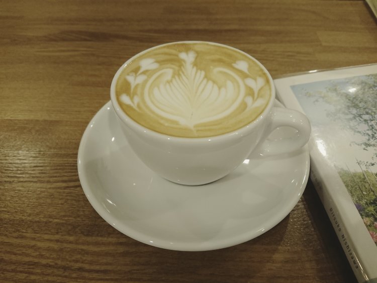 ポップコーンラテ（ホット／アイス）612円（テイクアウト600円）。今回はホットをチョイス。リーフとハートのカフェアートが可愛い。