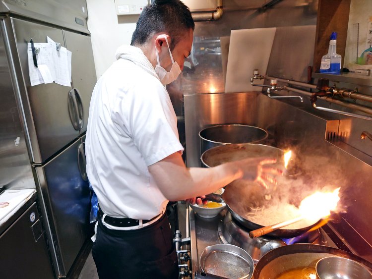 もやしを持ったまま鍋、火加減を見つめ、一気にジャッと投入。