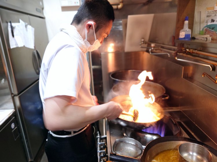 もやしを持ったまま鍋、火加減を見つめ、一気にジャッと投入。シャッキっとした食感にはこの絶妙なタイミングが大事。炎を上げながらガンガン煽って一杯分のスープが完成。