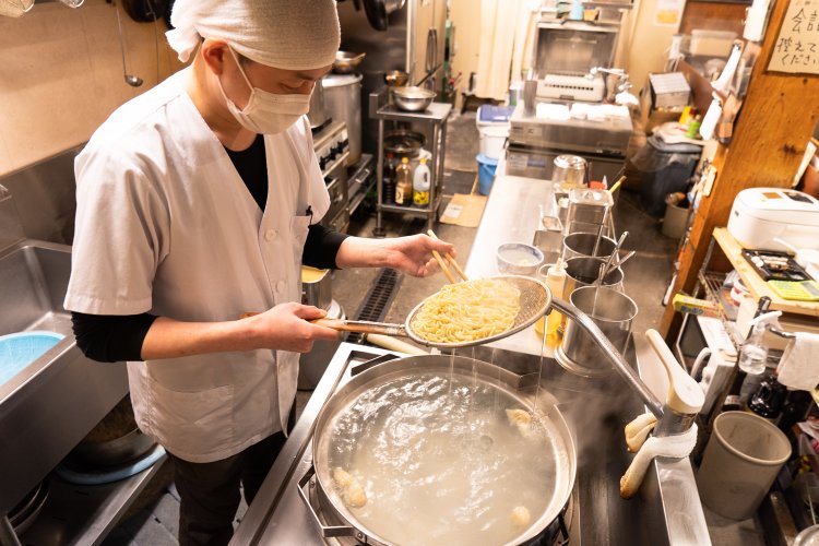 鍋の中で泳がせた麺を平ザルで湯切り。「この方法の方がおいしくなりますよ」と林さん。