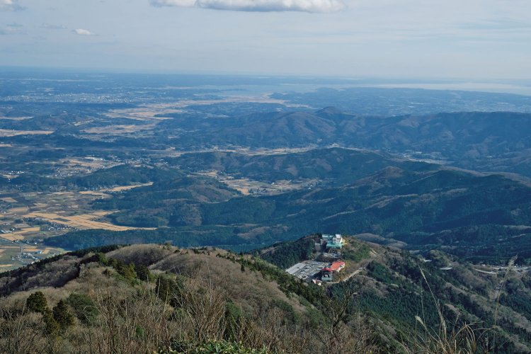 女体山山頂からの眺望。奥に霞ヶ浦の湖面が見える。手前下の建物はロープウェイ、つつじヶ丘駅。