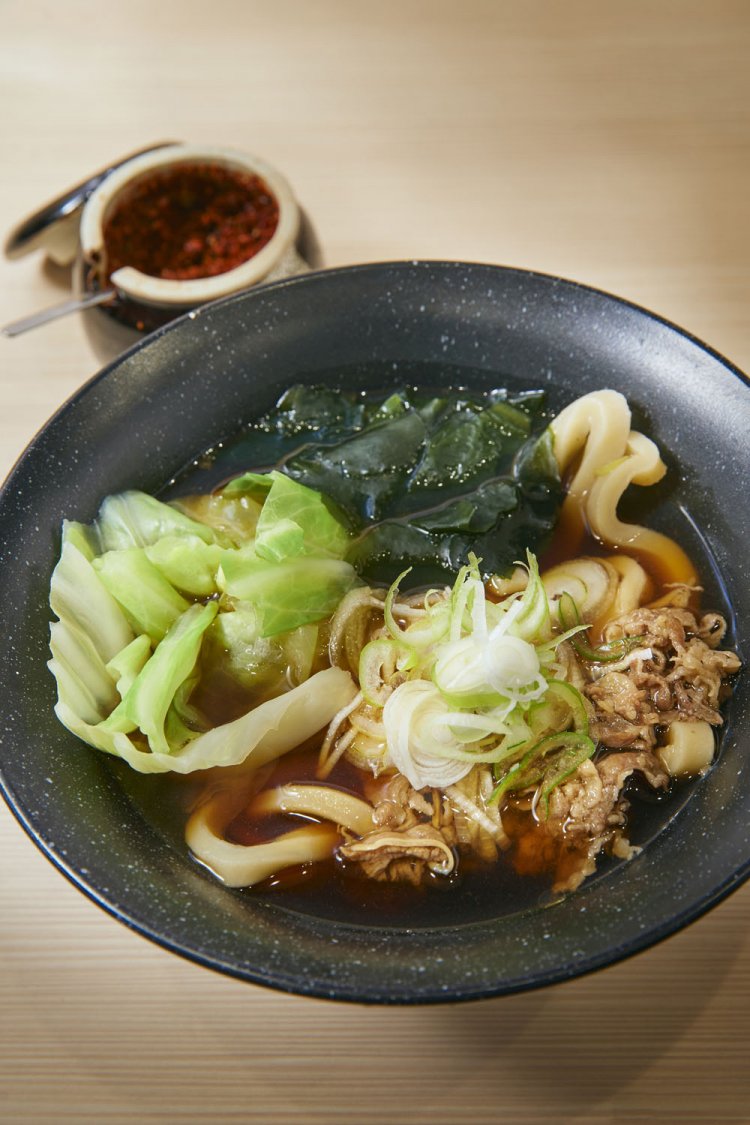 吉田の肉うどんは温200g600円。300g700円、400g800円から選べる。卓上のあげ玉、すりだねをお好みで。（価格変動あり）