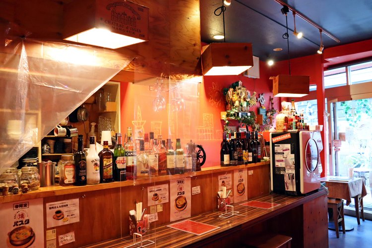 オレンジ色の壁が目を引く店内。カウンター席とテーブル席がある。