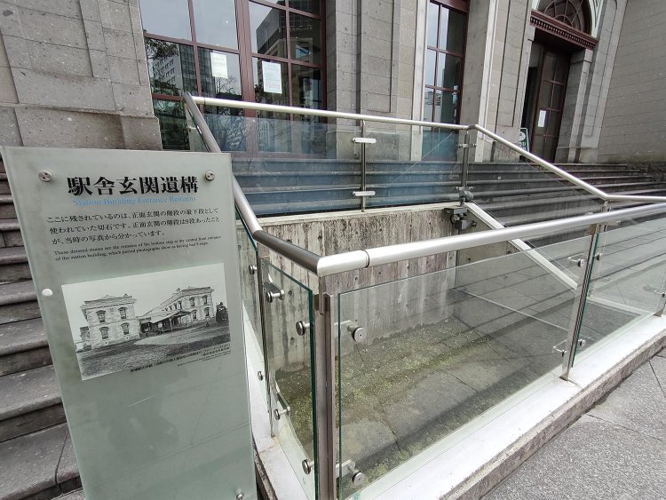 駅舎玄関には発掘されたときの遺構も見ることができる。説明版の古写真は開業当時のもの。