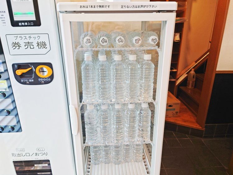 隣の券売機でプラ食券を購入し、冷蔵ケースからミネラルウォーターをセルフで1本取り出して席につく。