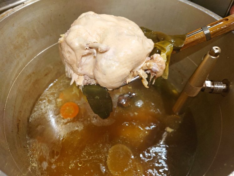 スープが炊けたら、圧力釜から大山鶏の丸鶏、香味野菜、昆布などを取り出す。