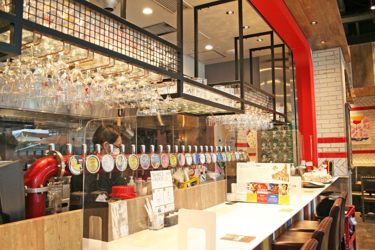 カウンター席の目の前に並ぶ生ビールサーバー。樽生ビールは常時12～13種類用意されている。