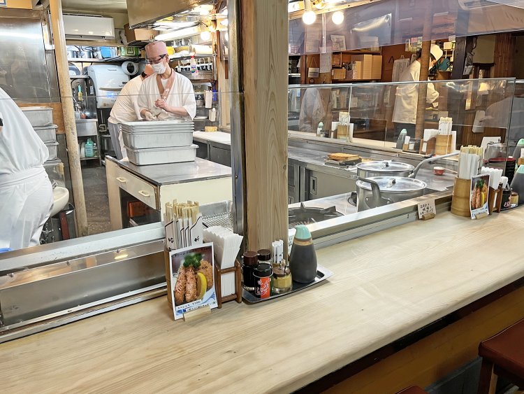 １階はL字のカウンターとテーブル席。オープンキッチンで調理の様子も見られる。