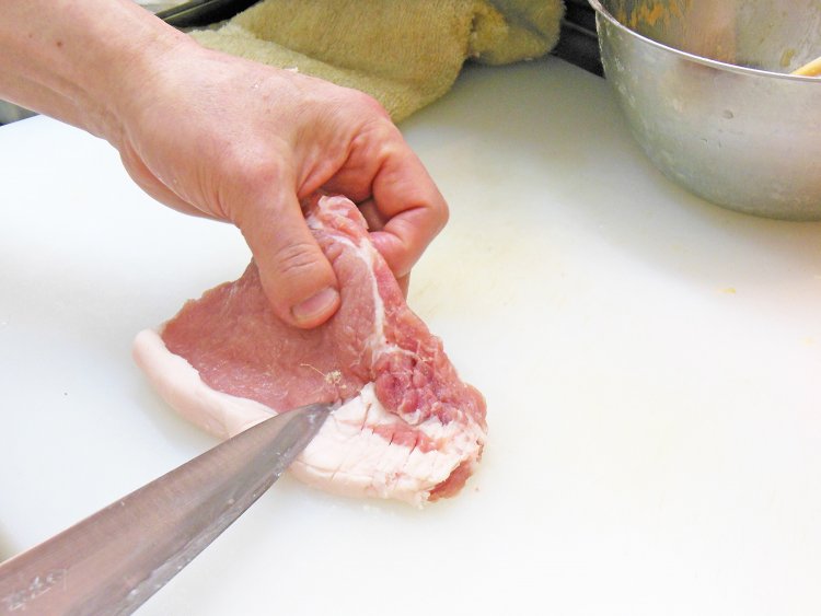 揚げたときにお肉が丸まらないように筋切りしたあと、脂身によく火が通るように隠し包丁を入れている。