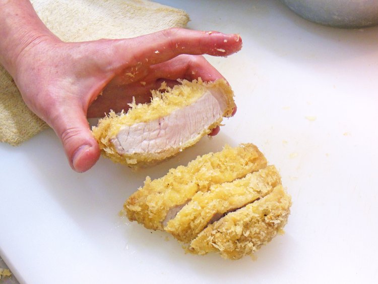 揚げたてのロースかつを牛刀で手早く切る。赤身の中心はほんのり桜色。「余熱で仕上がっていくこの状態がベスト」と秀巳さん。