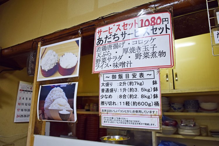 店内に貼り出された「御飯目安表」。一番少ないのが「擦り切れ：11軽（約600ｇ）」で、桶にご飯が盛られる。それより上は大きな鉢に盛られる。