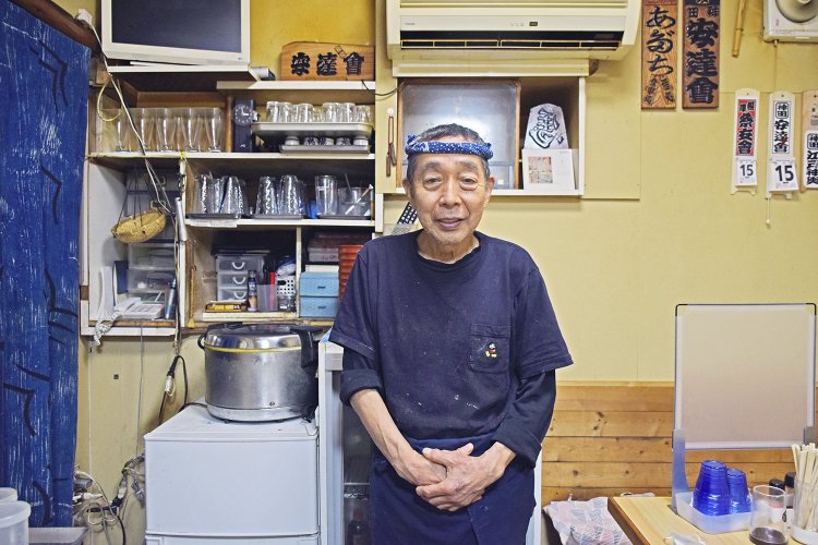 とにかく元気で明るい店主の安達政則さん。初めて訪れたお客さんには、驚愕のご飯盛りの流儀を丁寧にレクチャーする。