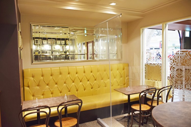 背もたれ部分がボタン止め装飾のクラシカルなイエローのソファーや、効果的に配された鏡が店内の狭さを感じさせない。