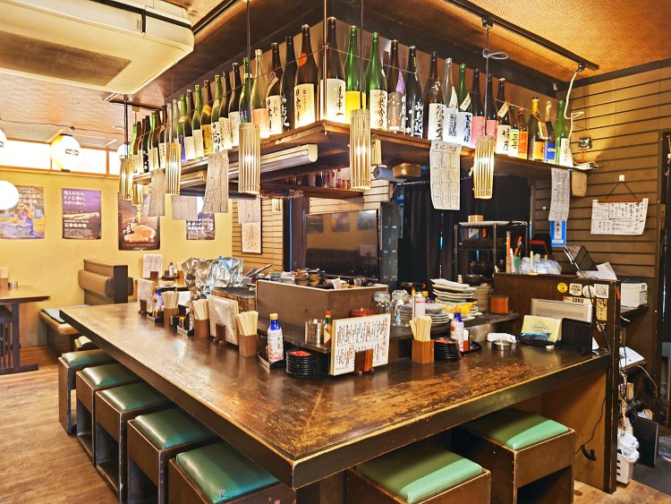 人との縁を大事にするオーナーこだわりのコの字カウンターが店の中心にドンと構える。