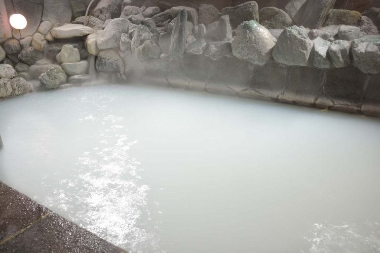 露天にある草津の湯。野趣あふれる岩組みの浴槽が温泉情緒を演出する。