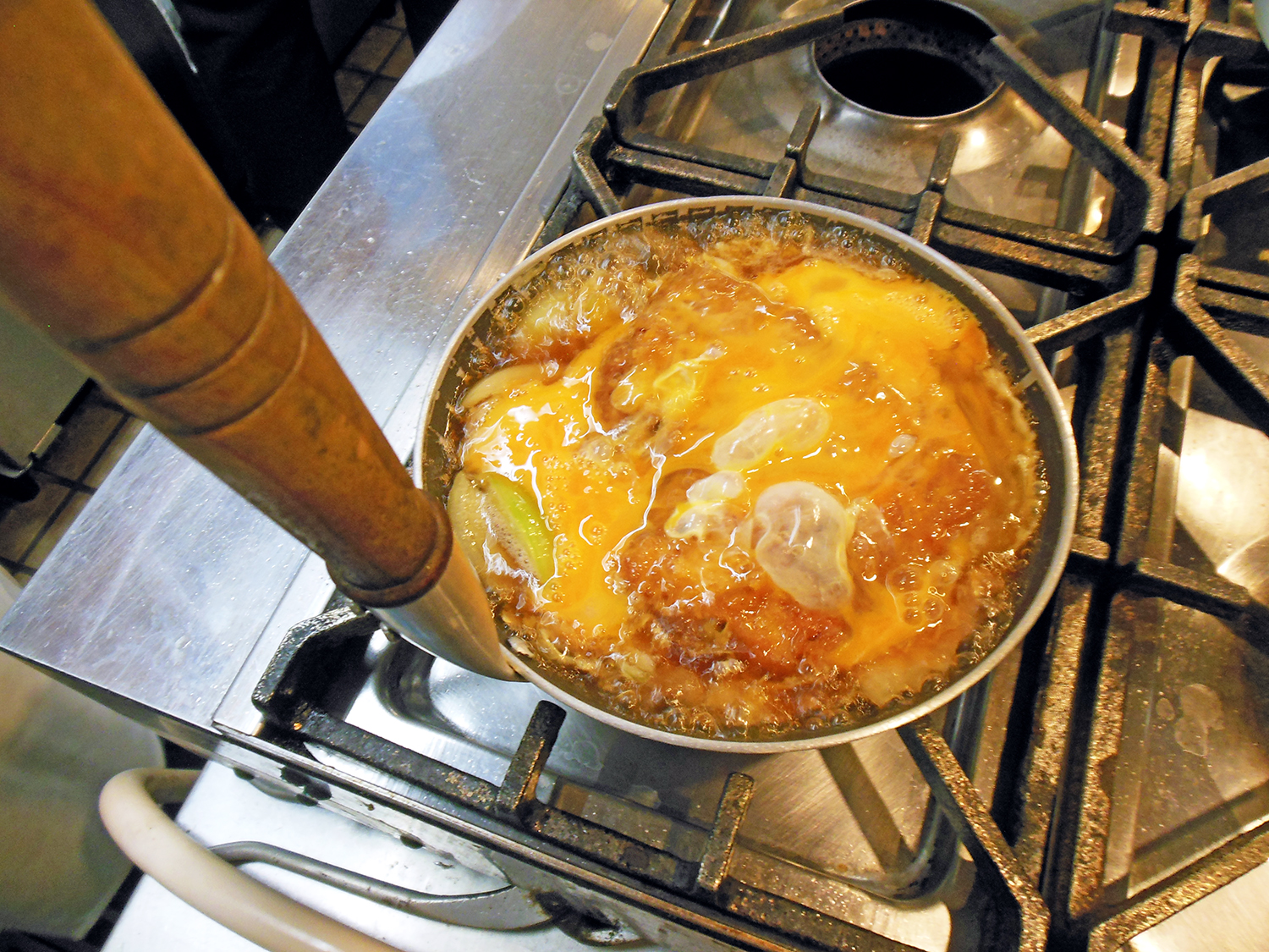 熱々のこんがりロースかつが、熟練した鮮やかな手さばきと火加減であっという間に見事な卵とじに。