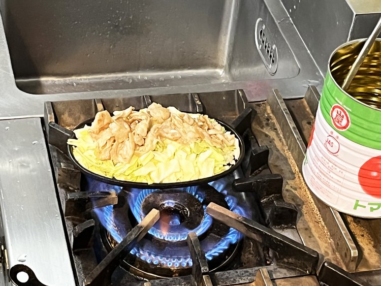 キャベツの上にソテーしたもち豚を乗せて鉄板を直火にかける。