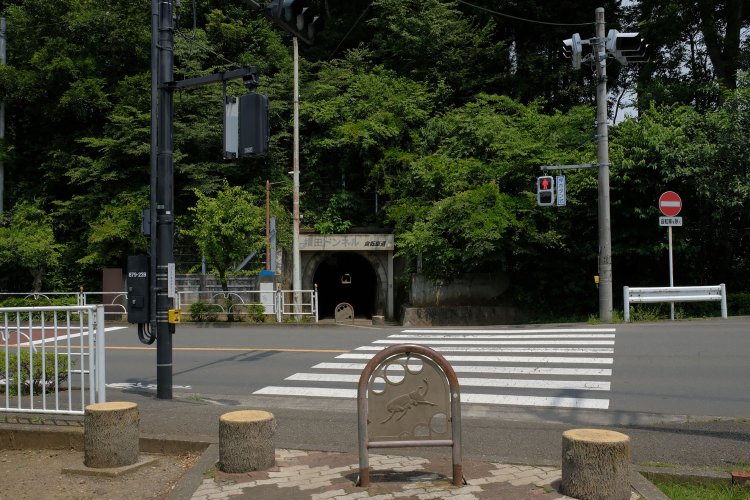   都道の先の丘陵にぽっかり口を開ける横田トンネル。この先は軽便鉄道廃線跡の醍醐味が味わえる連続トンネル区間である。