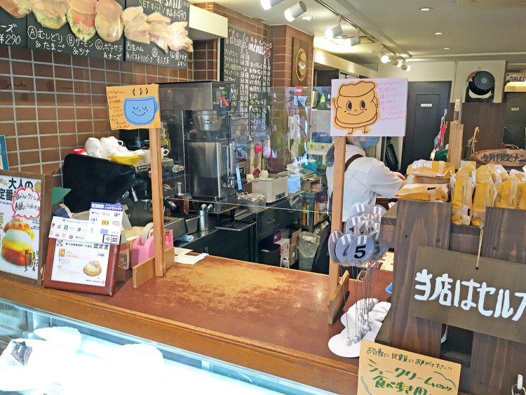 入って左側にあるカウンターで注文。手描きのポップがキュート。料理は番号札を受け取って席で待つスタイル。