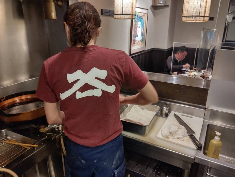 『やまいち』の屋号入りのTシャツを着て厨房に立つ松井里絵さん。