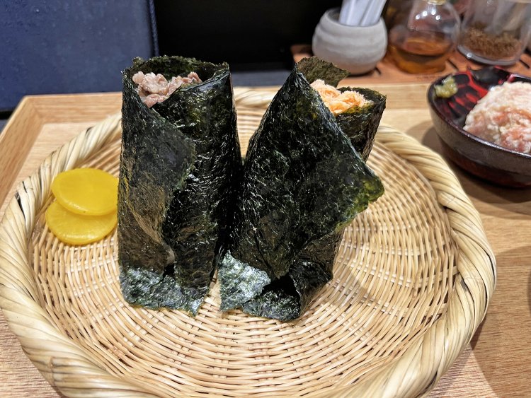 上等な有明産海苔に包まれたおむすびたち。ご飯の蒸気で海苔の豊かな香りが立ちのぼる。右が鮭で、左は牛すき山椒。