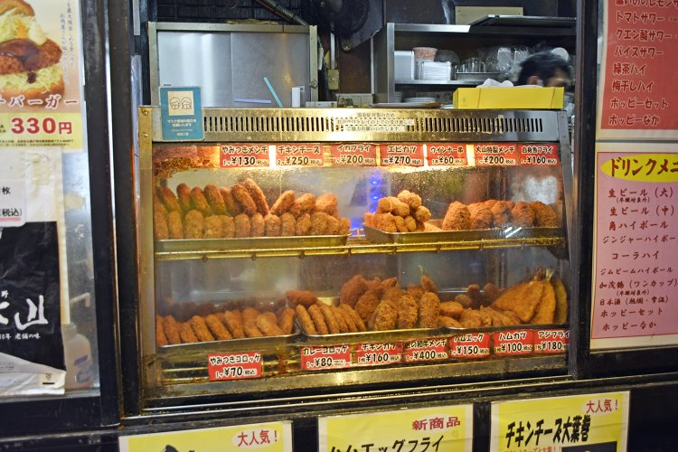 名物やみつきコロッケ70円、やみつきメンチ130円のほか、1日各150個売れる大山特製メンチ200円と匠の和牛メンチ400円は売り切れご免の人気商品。※価格は立ち飲みとテイクアウトでの価格