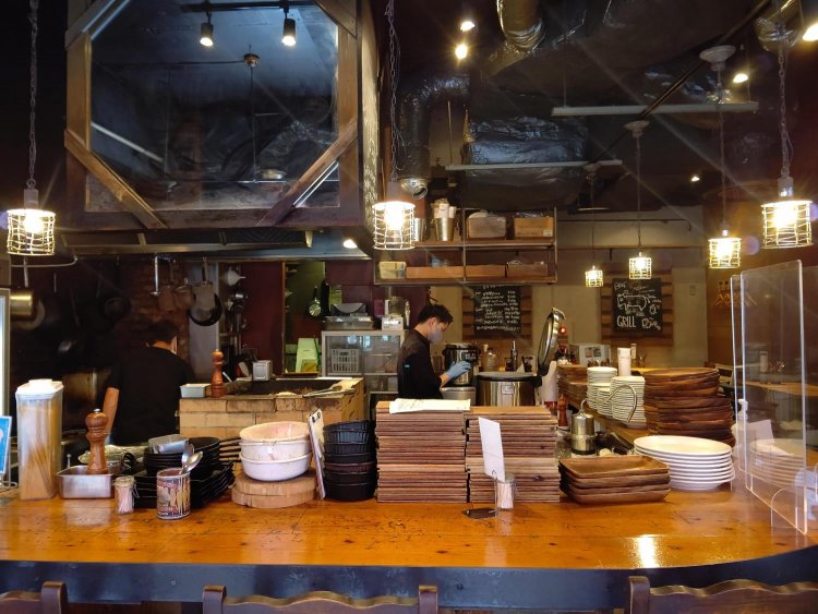 むき出しのダクトや間接照明のでざいんもしゃれている。カウンター席からはレンガ造りのBBQグリルも見える。