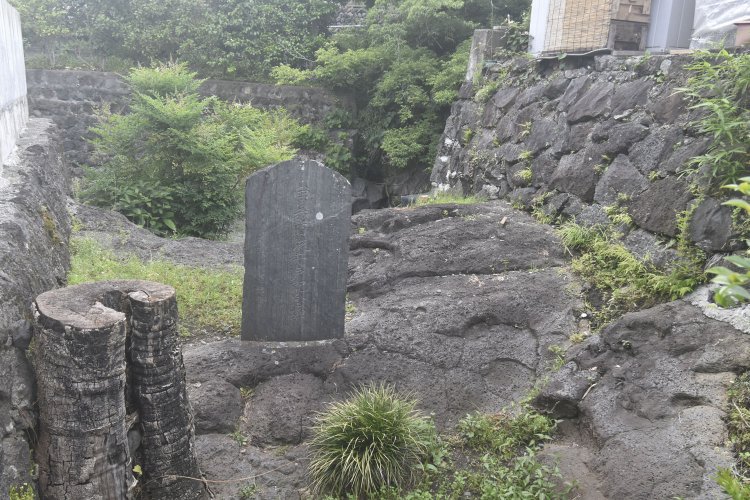 住宅に挟まれた小さな空き地に建つ五郎の首洗い井戸の碑。