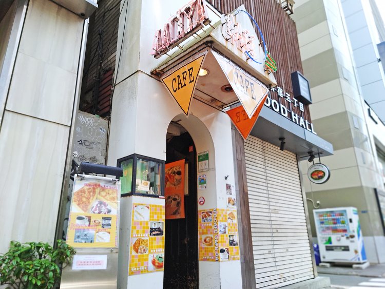 明治通り沿いのビル入り口を飾るネオンサインと黄色いCAFE旗が遠くからでも目立つ。
