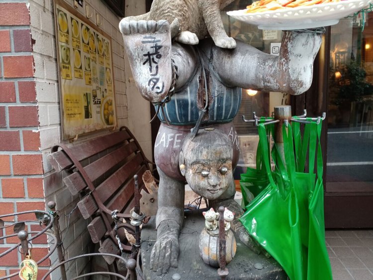 猫の彫刻の下にいる謎の人物。こどものように見える