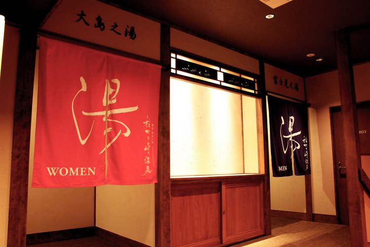 ぬくもりのある照明と重厚な木のあしらいに鮮やかな暖簾が際立つ。