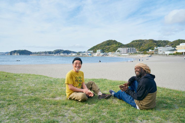 「この後ろの浜辺に今年もセルフビルドするよ～」　朝山さんとジャマイカ料理担当のトゥイッチさん。笑顔が素敵。