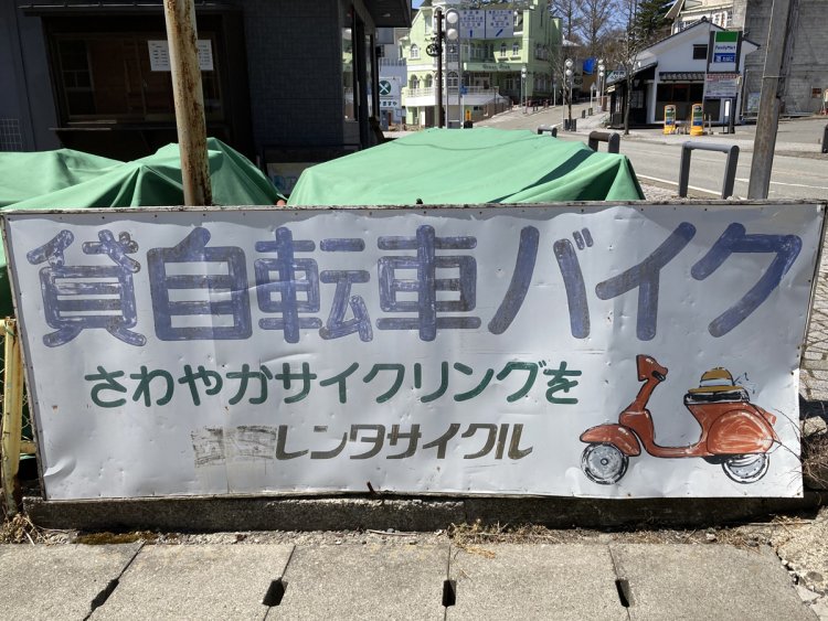 バイク駐輪場ではないが、清里の貸バイク店の看板。シート上に置かれた麦わら帽子がリゾート感を出している。