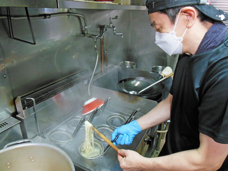 50℃以上の暑さの厨房で調理する店長の籔禎久さん。
