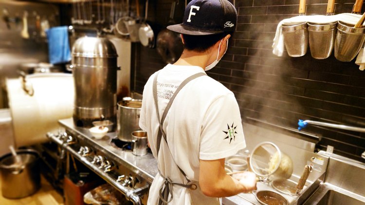 茹で麺機に向かってテボで一杯ずつ茹でる本田さん。