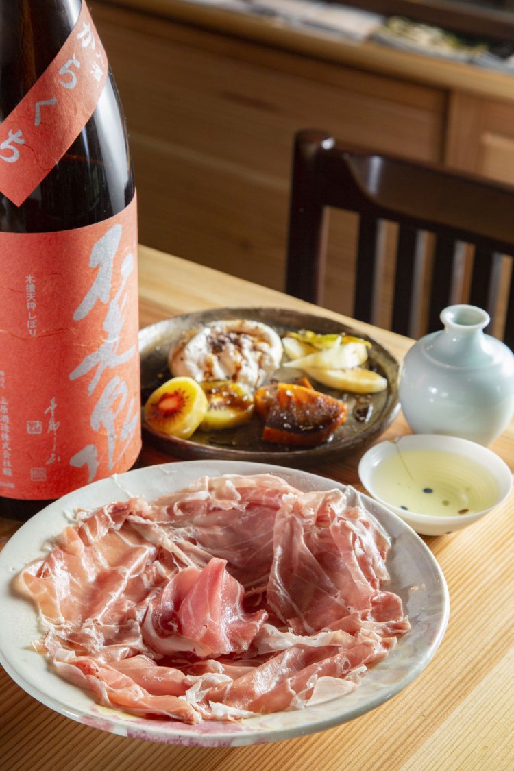 生ハム1500円～、ブラータチーズと季節のフルーツ1500円～（季節のフルーツの価格による）。独特のクセと旨味が生ハムに合う「不老泉」を燗酒で。