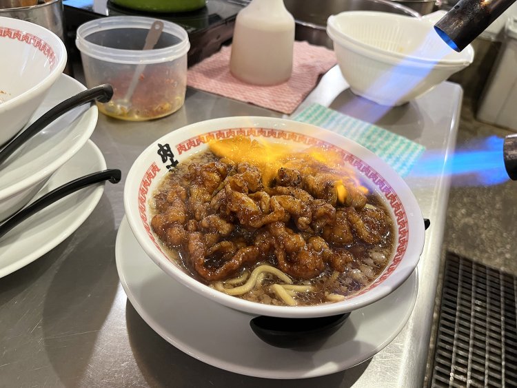 ラーメンの上に乗せ、最後はバーナーで表面をあぶり仕上げていく。