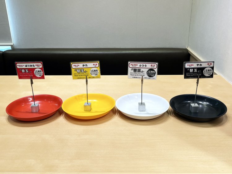 色で麺の硬さがわかる替玉札＆皿。外国人のために、札には「KA-TA（Hard）」「YA-WA（Soft）」と発音を併記する工夫も。