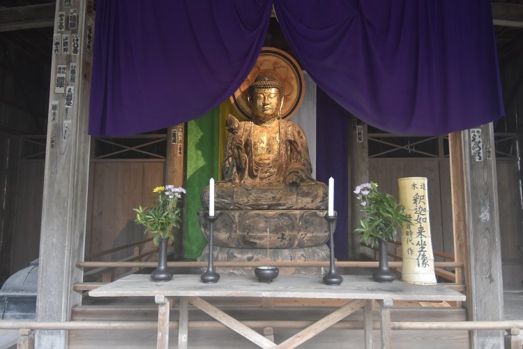 開かれた扉から拝むことができる、ハスの花を持つ釈迦如来坐像。