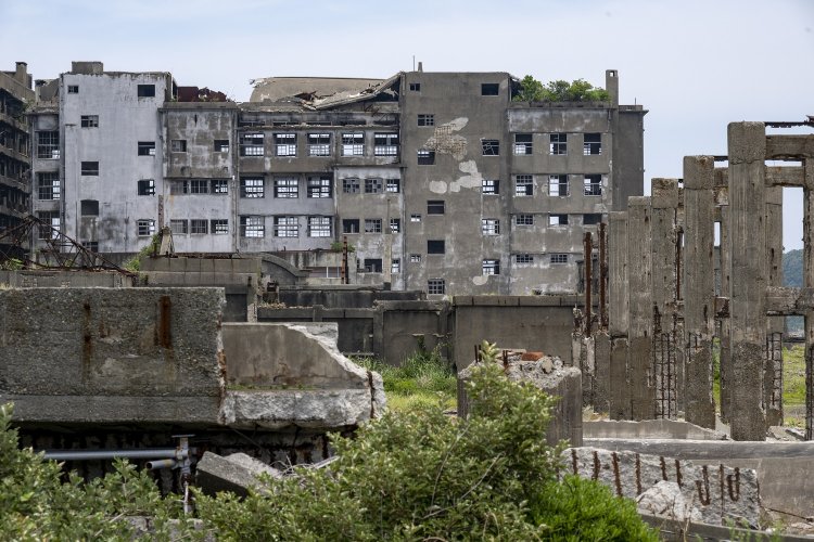 帰りがけに、もう一度端島小中学校を見る。校舎の屋上は植物が自生していた。手前右は貯炭場のベルトコンベヤー橋脚。柱にはうっすらと石炭が貯まって黒ずんだ跡が残る。