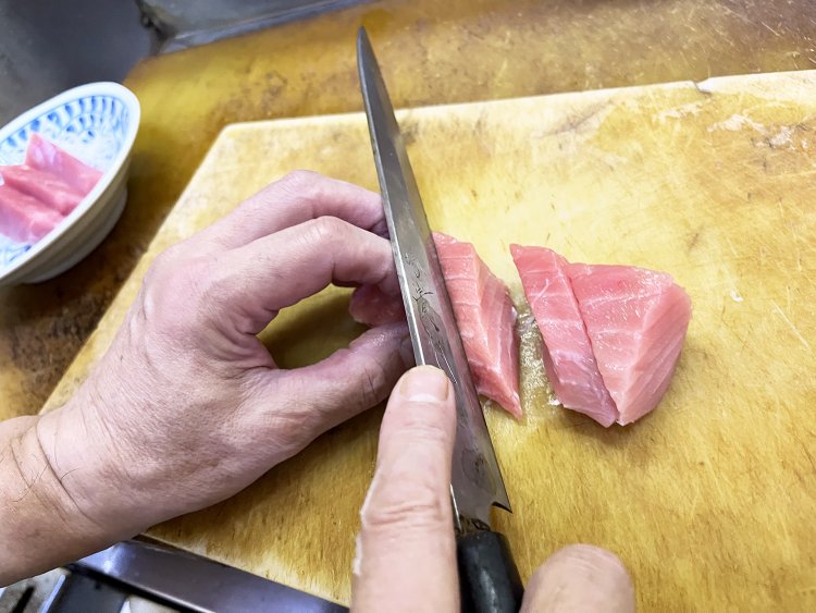 毎朝５時に起きて豊洲市場へ仕入れに行き、下ごしらえをして昼は仕入れたマグロを切る智晴さん。