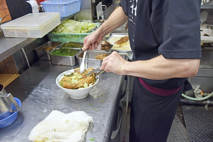 究極にやわらかく煮込まれた太肉を、トング2本を使って丁寧に盛り付け。力加減に気をつけないと、すぐに崩れてしまう。