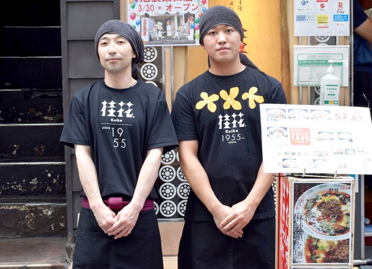 『桂花ラーメン』の味をしっかり守る店長の吉田弘幸さん（左）と、副店長の秋山大駿さん。Tシャツに描かれたオレンジ色の花は、桂花（=きんもくせいの中国名）。